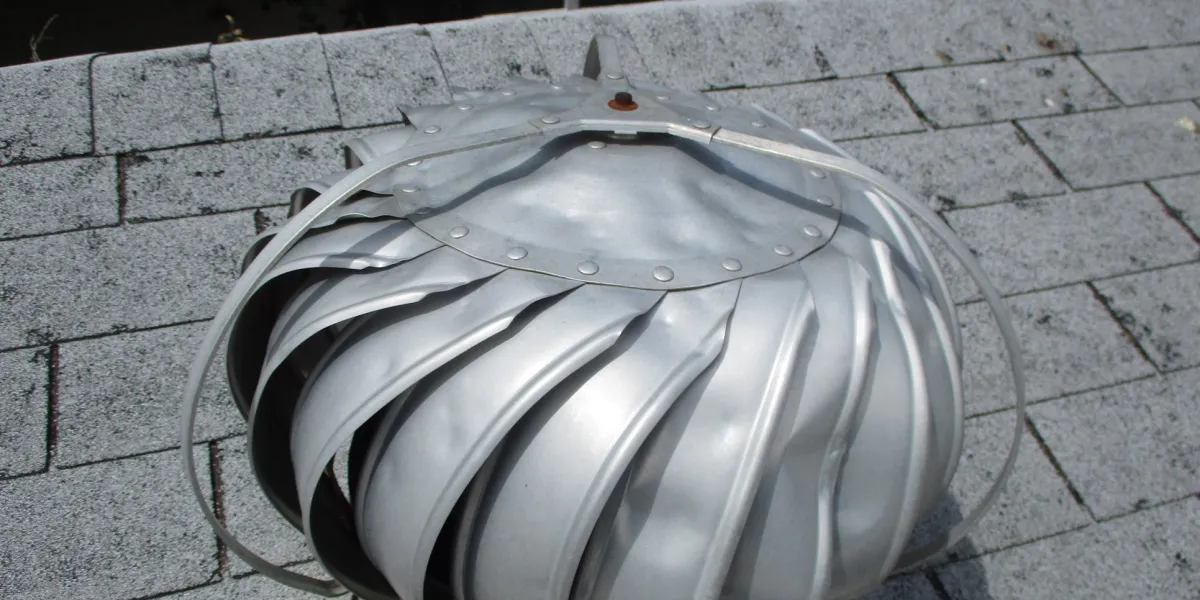 Dented metal turbine vent on a shingle roof