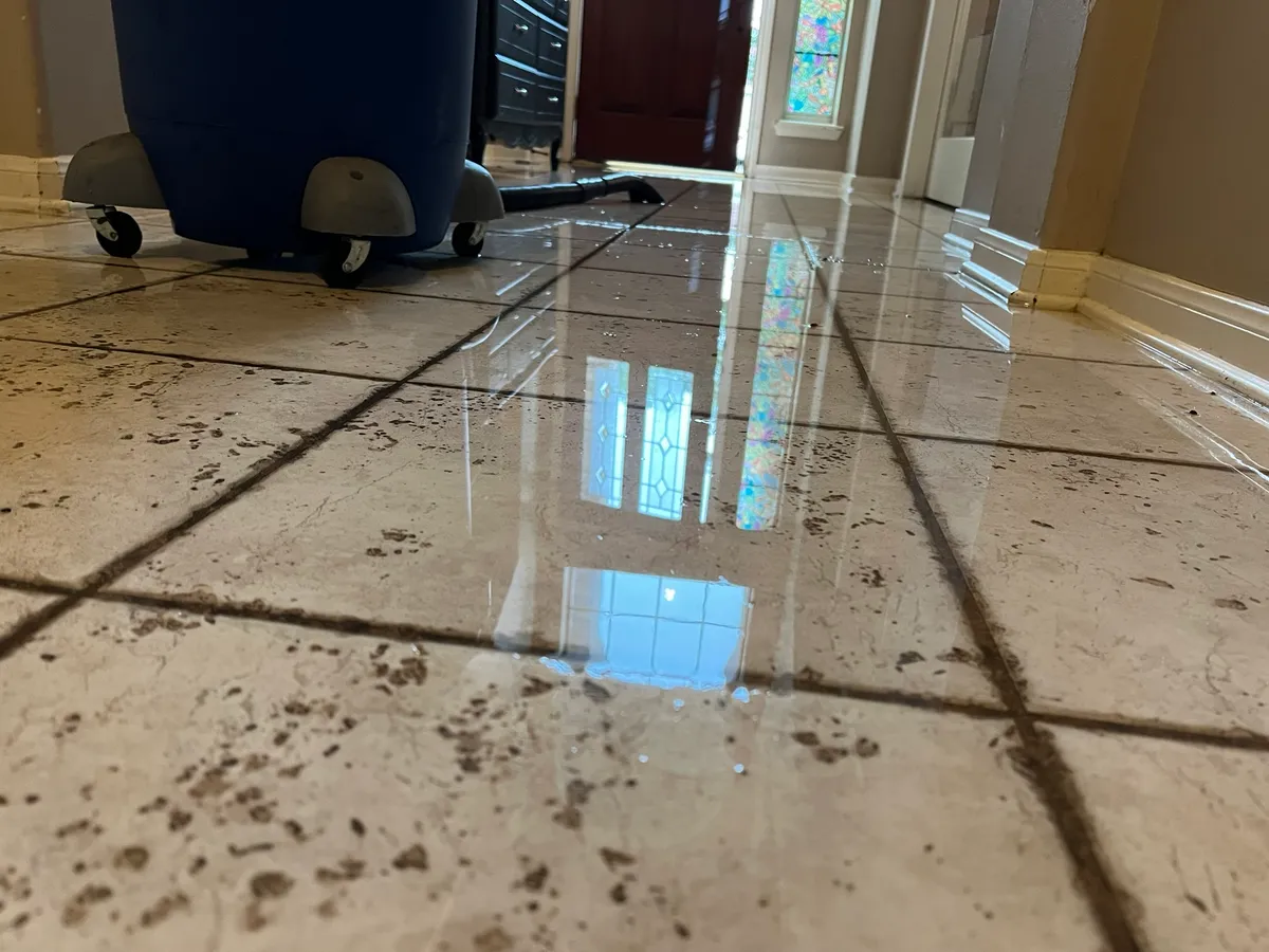 Standing water on a tile floor with a wet vacuum in a hallway